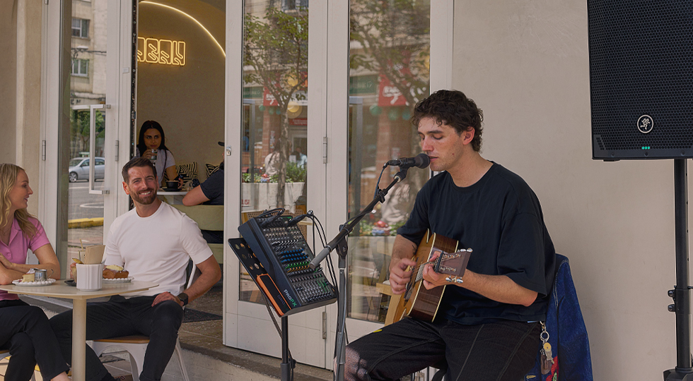 Musician singing and playing guitar using ProFX mixer and Thumpv4 loudspeaker.