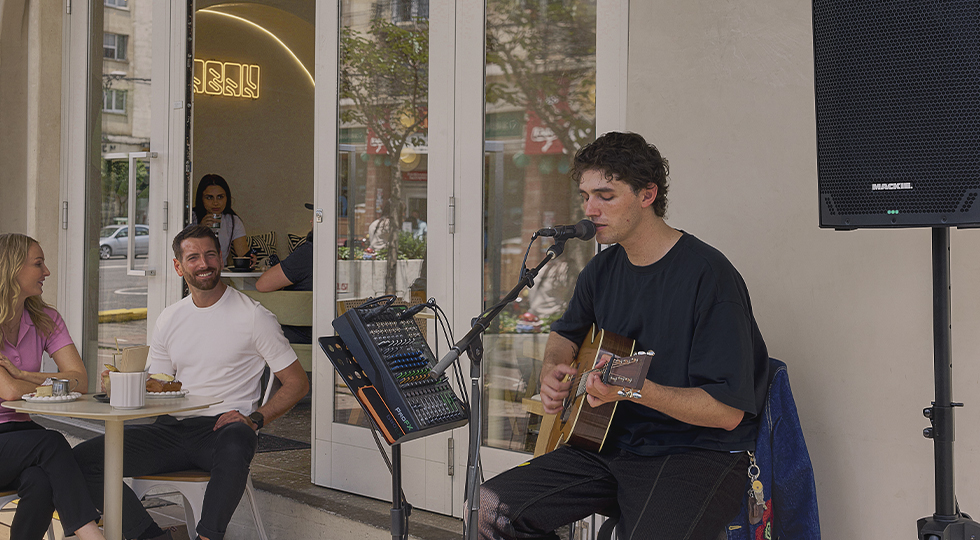 Musician singing and playing guitar using ProFX mixer and Thumpv4 loudspeaker.